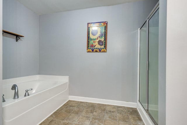 bathroom with a garden tub, baseboards, and a shower stall