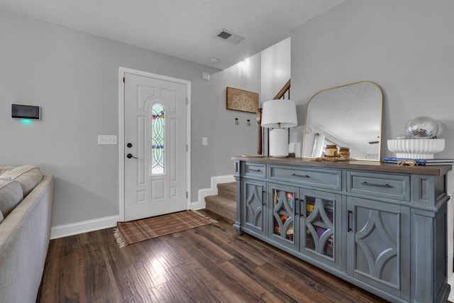 entryway featuring baseboards, dark wood-style flooring, stairs, and visible vents
