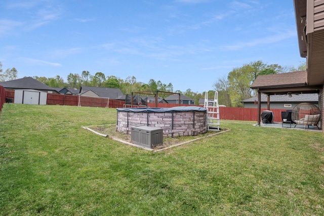 view of yard with a fenced in pool, a fenced backyard, a storage shed, a patio area, and an outbuilding