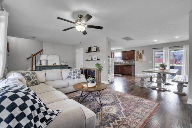 living area with baseboards, a ceiling fan, visible vents, and dark wood finished floors