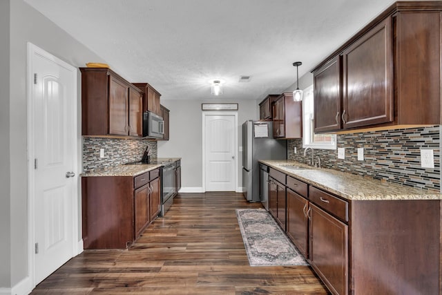 kitchen with stainless steel appliances, a sink, dark wood finished floors, baseboards, and backsplash