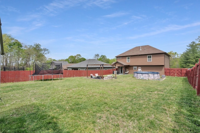 view of yard featuring a fenced backyard, outdoor lounge area, a trampoline, and a swimming pool