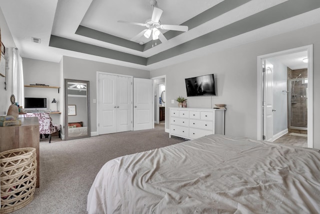 bedroom with a raised ceiling, visible vents, ensuite bath, a closet, and carpet flooring