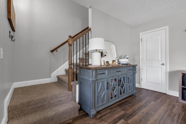 staircase with baseboards, wood finished floors, and a textured ceiling