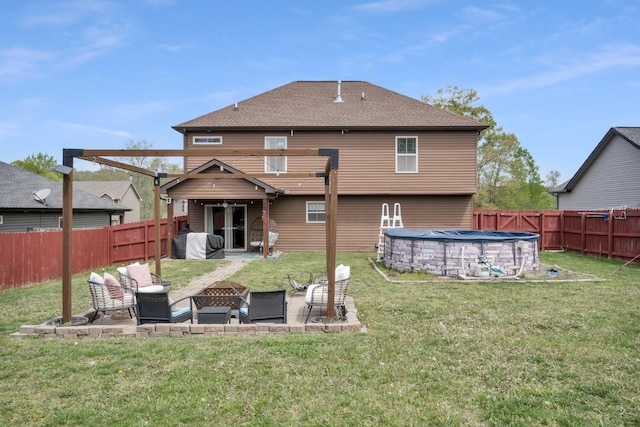 back of house with a patio area, a lawn, a fenced backyard, a fire pit, and a fenced in pool