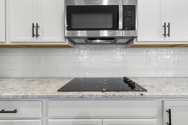978 Alton Dr, Clarksville, TN 37043 - kitchen with stainless steel microwave, decorative backsplash, white cabinets, and black electric cooktop