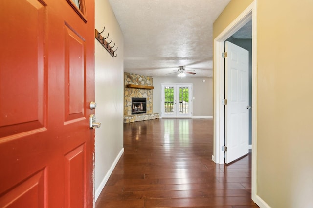 interior space featuring dark wood finished floors, a ceiling fan, a textured ceiling, and a fireplace