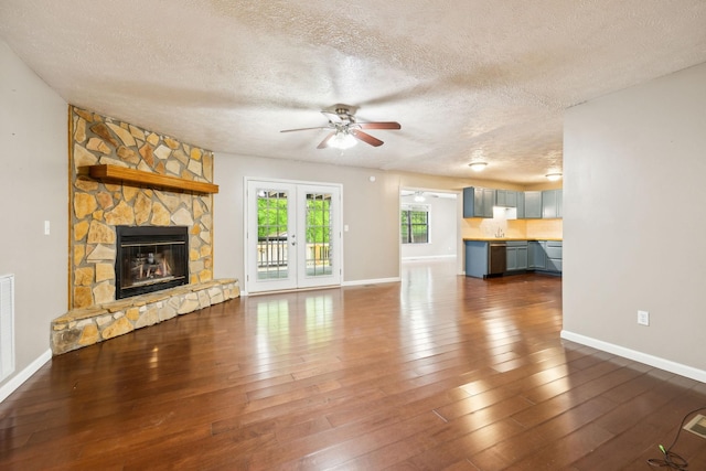 unfurnished living room featuring a textured ceiling, a ceiling fan, baseboards, and dark wood finished floors