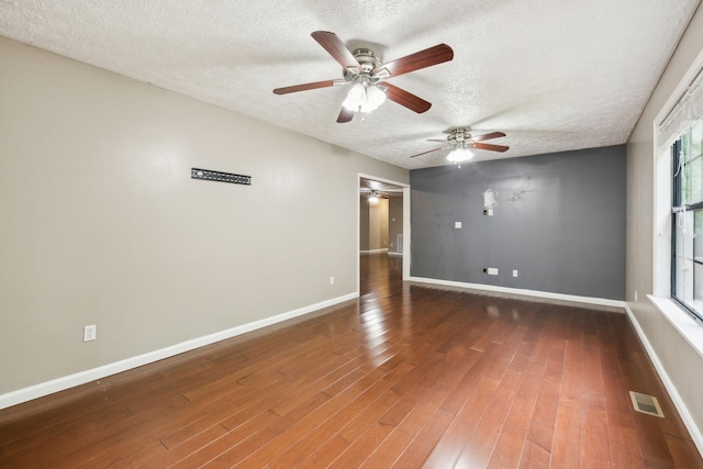 spare room with wood finished floors, ceiling fan, baseboards, visible vents, and a textured ceiling