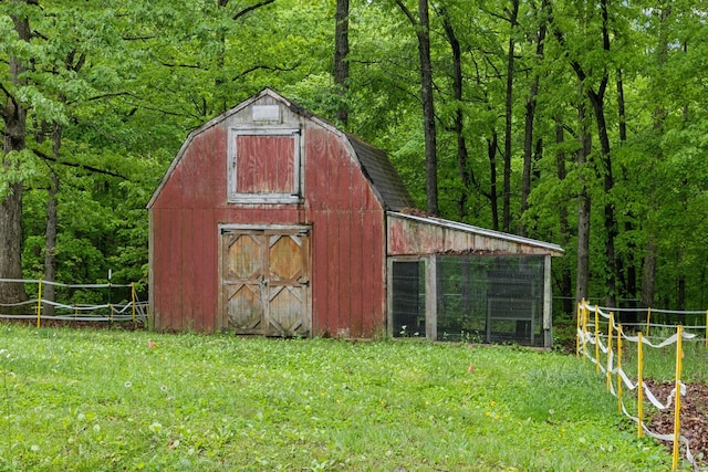view of barn with a lawn and a view of trees