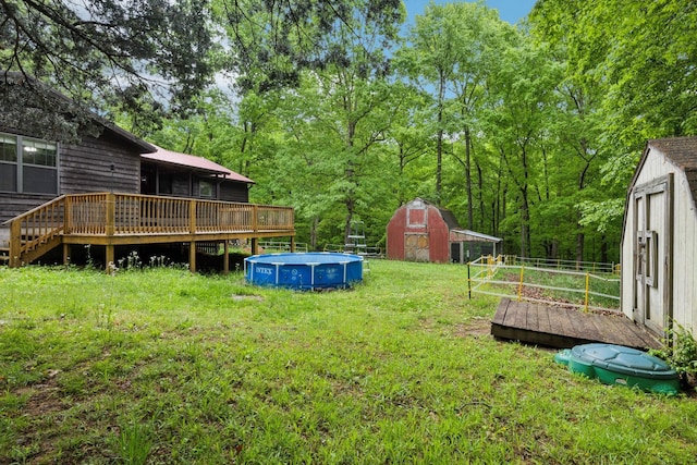 view of yard featuring a wooden deck, a shed, an outdoor pool, and an outdoor structure