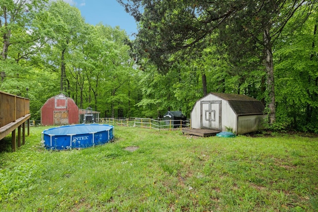 view of yard featuring fence, a storage shed, a fenced in pool, and an outdoor structure