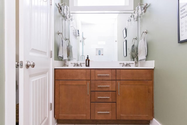 bathroom with a shower stall, a sink, and double vanity