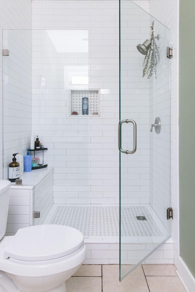 bathroom with toilet, a stall shower, and tile patterned floors