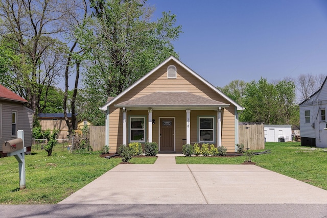 view of front of house with a front lawn, fence, a porch, and roof with shingles