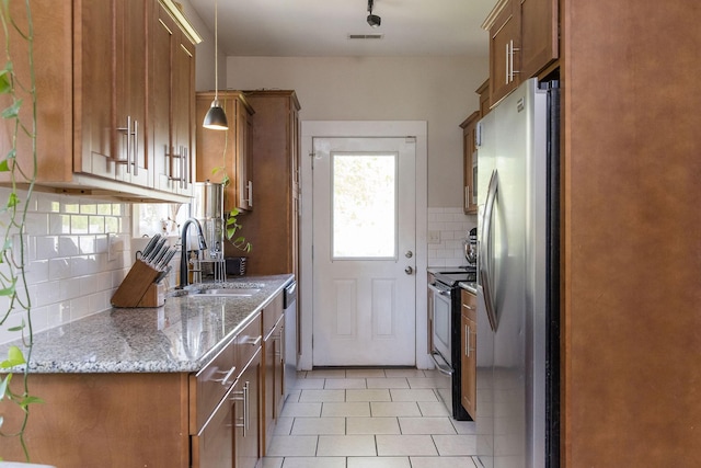 kitchen with brown cabinetry, a sink, appliances with stainless steel finishes, and tasteful backsplash
