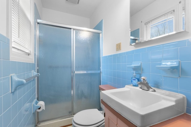 full bathroom featuring tile walls, toilet, wainscoting, and a stall shower