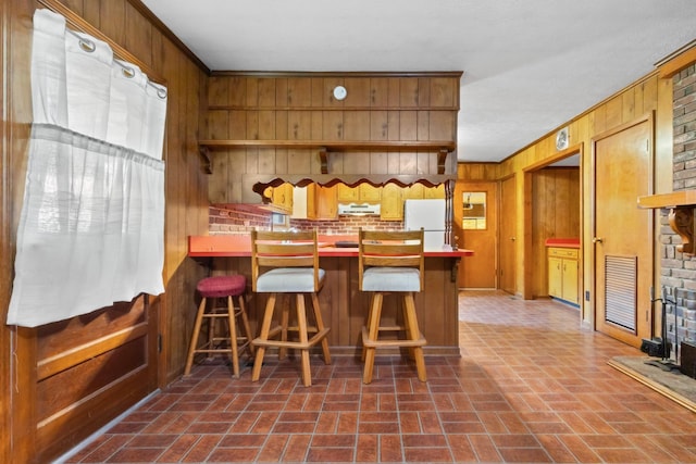 dining room with brick floor, wood walls, and ornamental molding