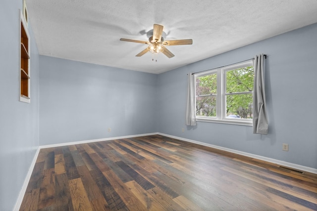 empty room with wood finished floors, visible vents, a ceiling fan, and baseboards
