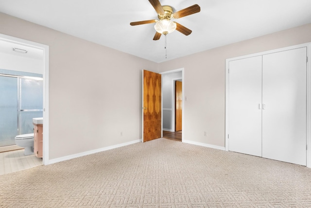 unfurnished bedroom featuring baseboards, carpet, a closet, ceiling fan, and connected bathroom