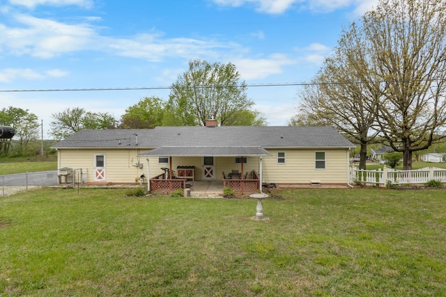 rear view of property featuring a lawn, a chimney, and fence