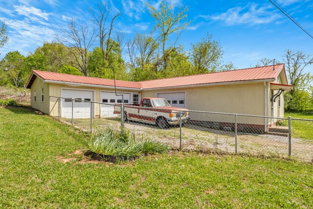 view of front of home with an attached garage, a front lawn, metal roof, and fence