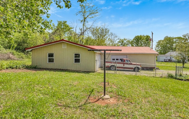 rear view of property with a lawn, fence, and metal roof
