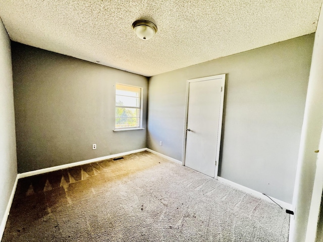 unfurnished bedroom featuring visible vents, baseboards, carpet floors, and a textured ceiling