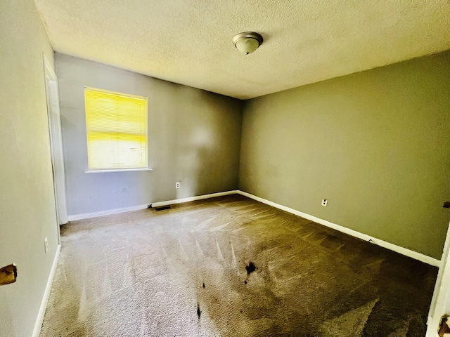 carpeted spare room with a textured ceiling and baseboards
