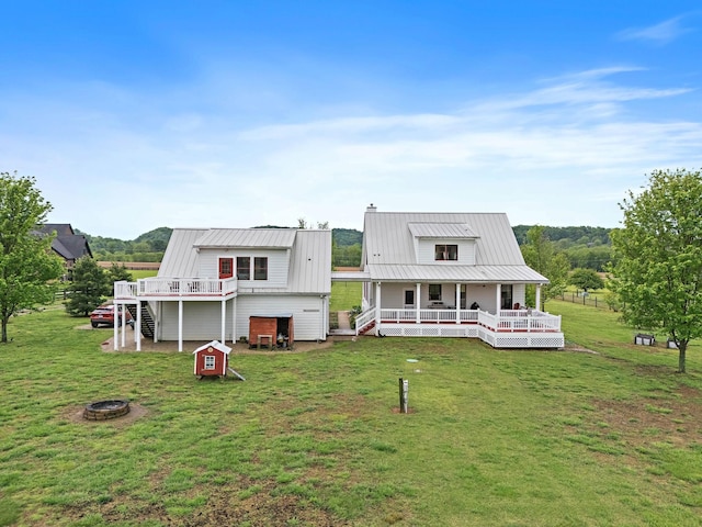 back of house featuring covered porch, a yard, a fire pit, and a chimney