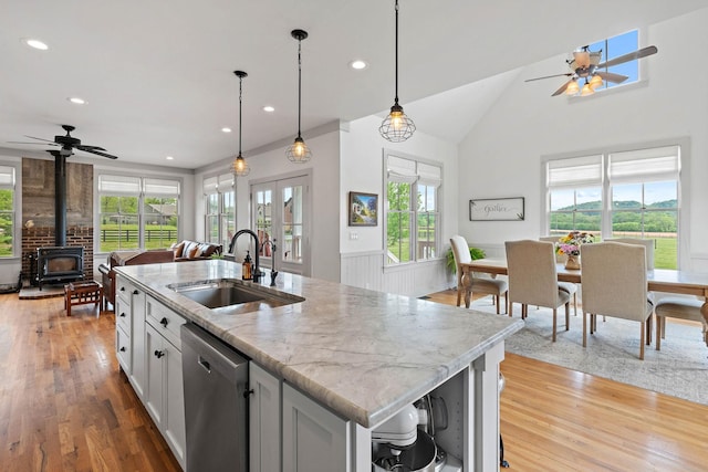 kitchen featuring a ceiling fan, a sink, a wood stove, and dishwasher