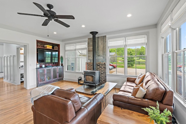 living area featuring light wood-style floors, a wood stove, ceiling fan, and recessed lighting