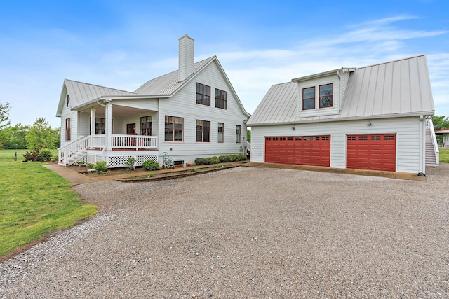 modern farmhouse style home with a garage, a chimney, metal roof, a porch, and driveway