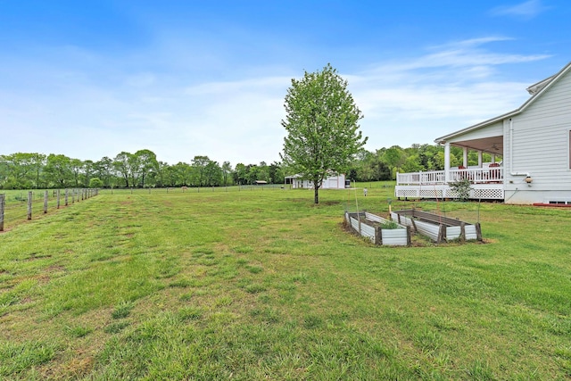 view of yard featuring a deck, fence, and a garden