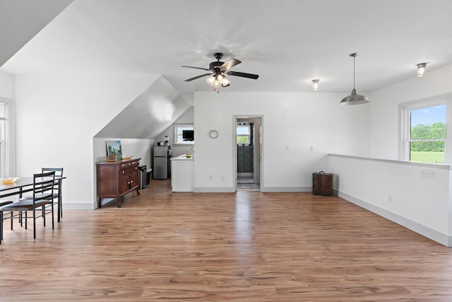 unfurnished living room featuring baseboards, a ceiling fan, and light wood-style flooring