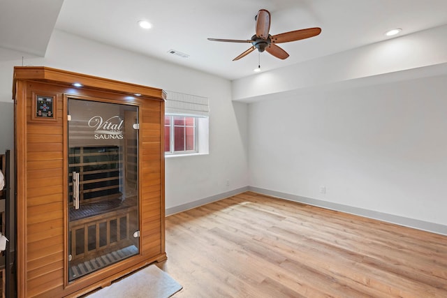 interior space featuring ceiling fan, baseboards, wood finished floors, visible vents, and a sauna