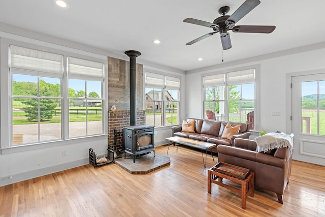 living area with recessed lighting, ceiling fan, wood finished floors, and a wood stove