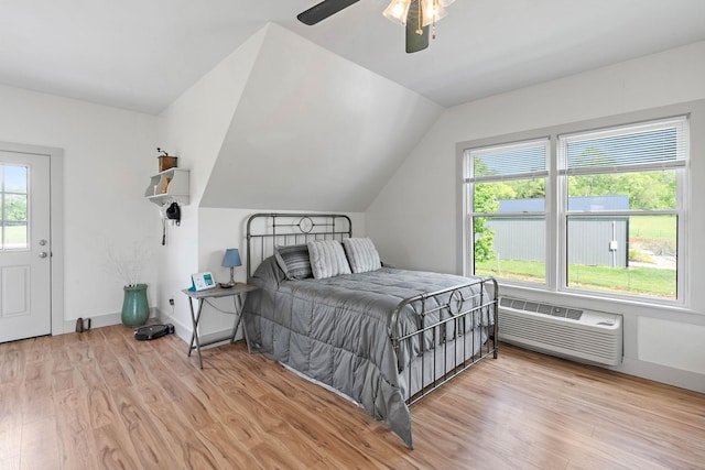 bedroom featuring multiple windows, a wall unit AC, and light wood-style flooring