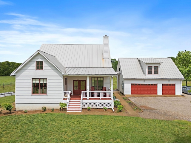 modern farmhouse with a front yard, french doors, a chimney, a porch, and a detached garage