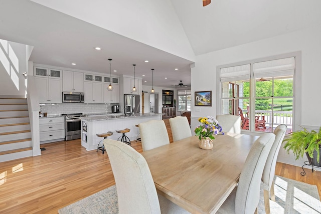 dining space with ceiling fan, stairway, high vaulted ceiling, recessed lighting, and light wood-style flooring