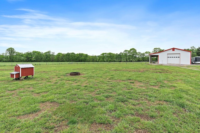 view of yard featuring a garage, fence, a pole building, a rural view, and an outbuilding