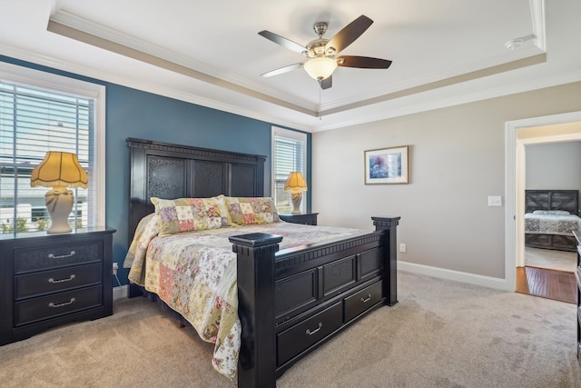 bedroom featuring a tray ceiling, light carpet, baseboards, and ornamental molding