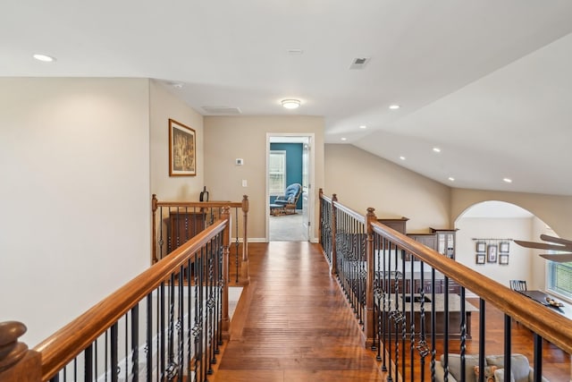 corridor featuring recessed lighting, vaulted ceiling, wood finished floors, visible vents, and an upstairs landing