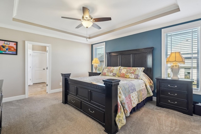 bedroom with baseboards, light colored carpet, a ceiling fan, crown molding, and a raised ceiling