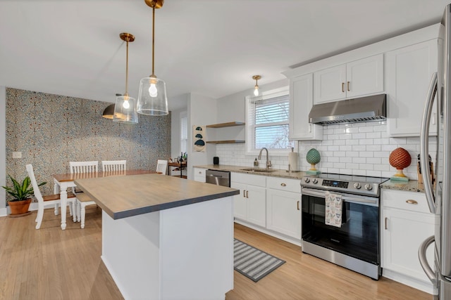 kitchen with white cabinets, under cabinet range hood, stainless steel appliances, and a sink
