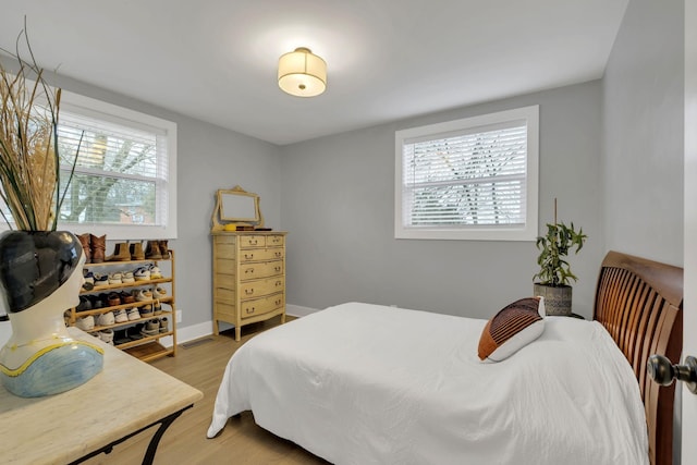 bedroom featuring light wood-type flooring, baseboards, and multiple windows