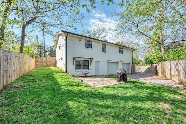 rear view of property with a fenced backyard, driveway, a yard, and a garage
