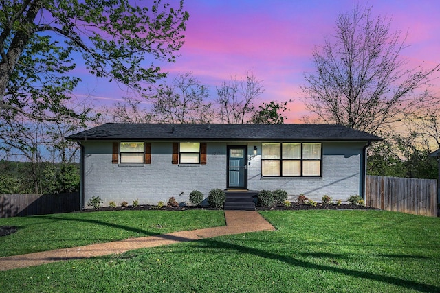 ranch-style house with brick siding, a lawn, and fence