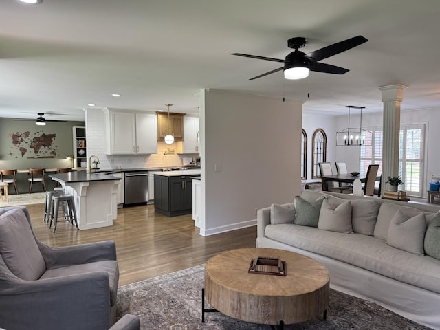 living area with baseboards, recessed lighting, wood finished floors, and ceiling fan with notable chandelier