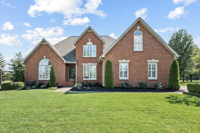 traditional home with a front lawn, roof with shingles, and brick siding